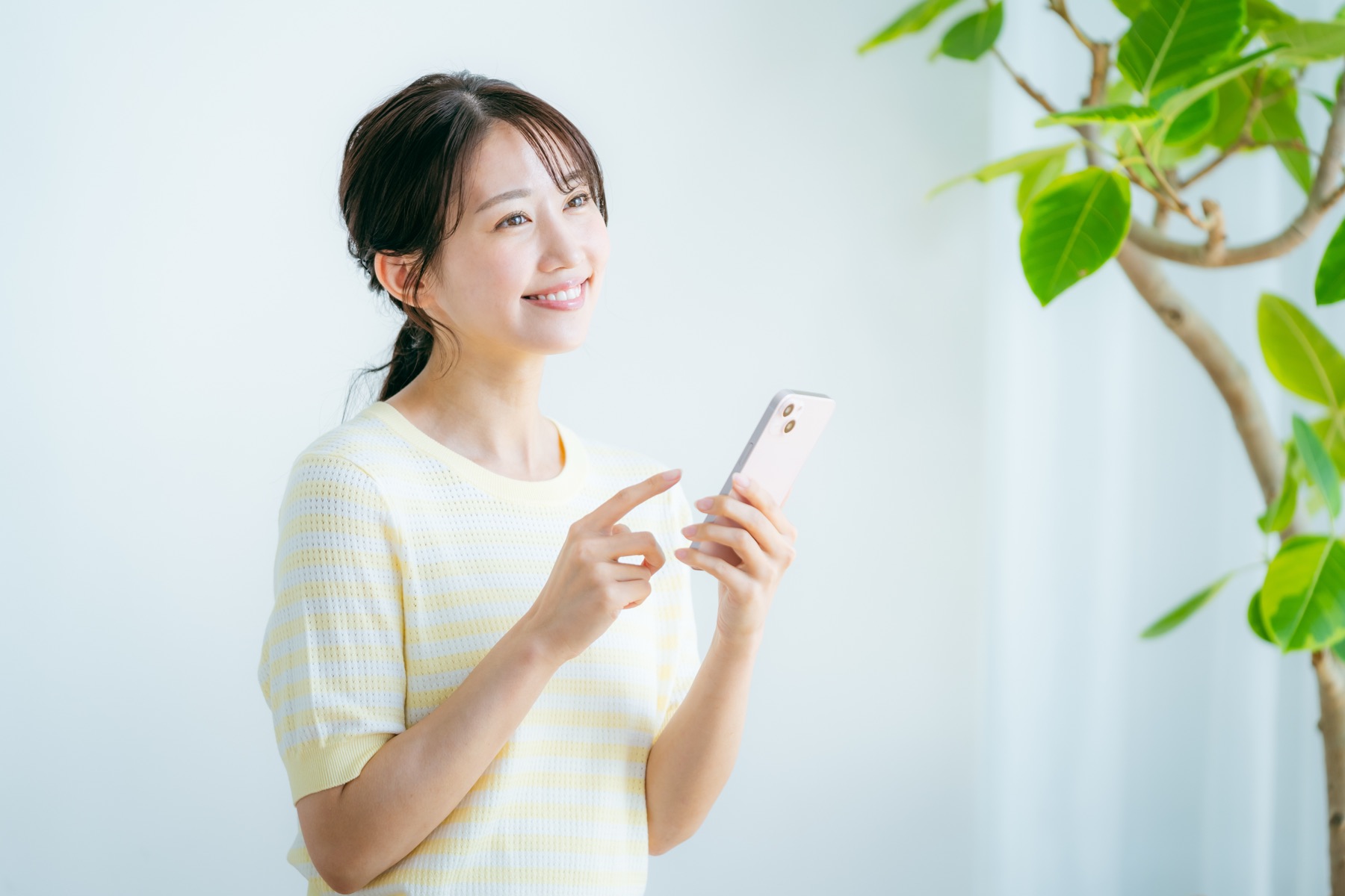明るい部屋でスマホを操作して微笑む女性